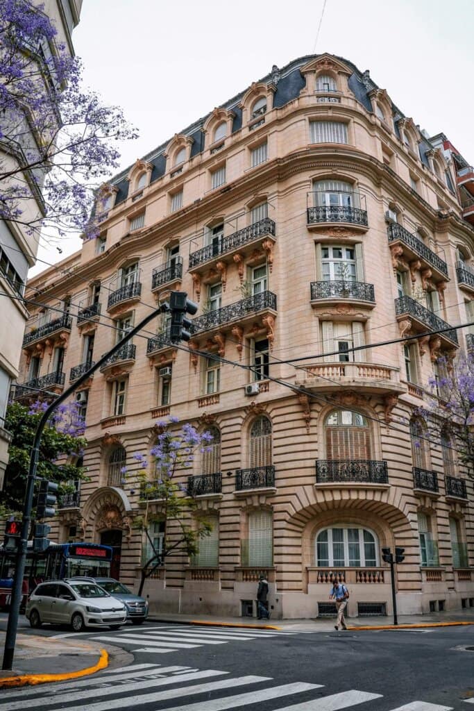 Fachada patrimonial de esquina con balcones de herrería y jacarandás